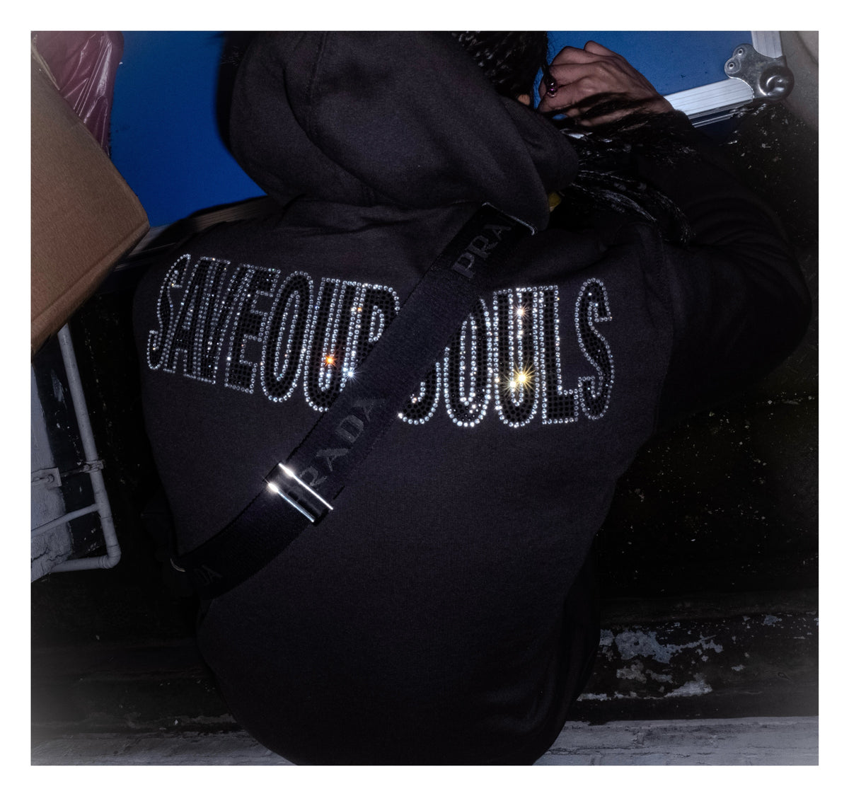Back view of a black hoodie with SAVE OUR SOULS lettering outlined in rhinestones.