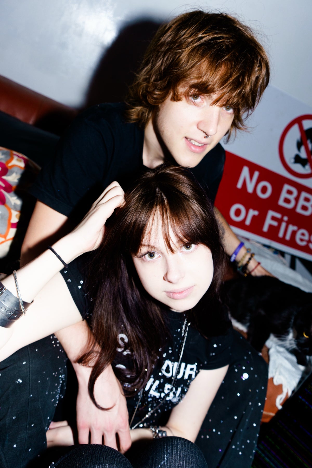 Two models wearing black SOS tops indoors, with rhinestone jeans in the foreground.