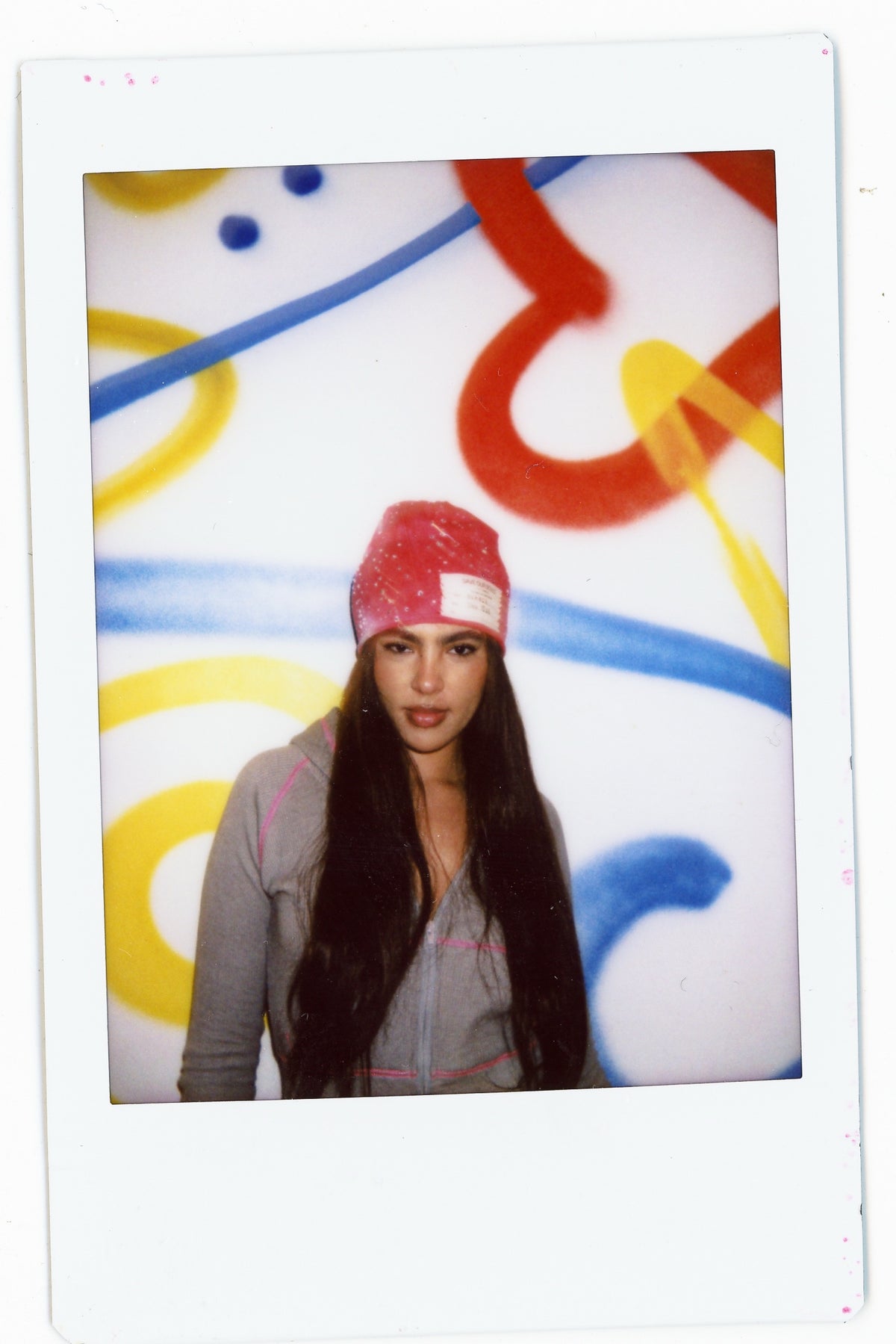 Instant photograph of a model wearing a red rhinestone beanie.